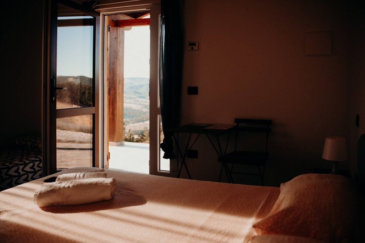 Une chambre d’hôtel avec un lit, une petite table, une chaise et une vue sur l’extérieur.