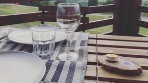 A table set with plates, glasses, and a wine glass on a striped tablecloth, overlooking a mountainous landscape. - Azienda Agricola Saint Hubert (Cantalupo Ligure)
