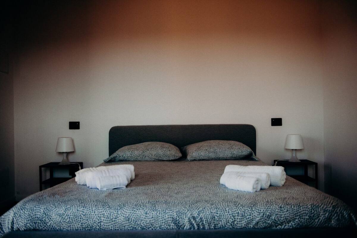 Un lit bien fait, avec une couvre-lit à motifs, deux oreillers et deux tables de chevet dotées de lampes.
