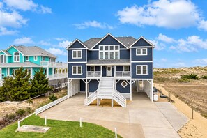 A two-story house with a front porch and a staircase leading to a deck.