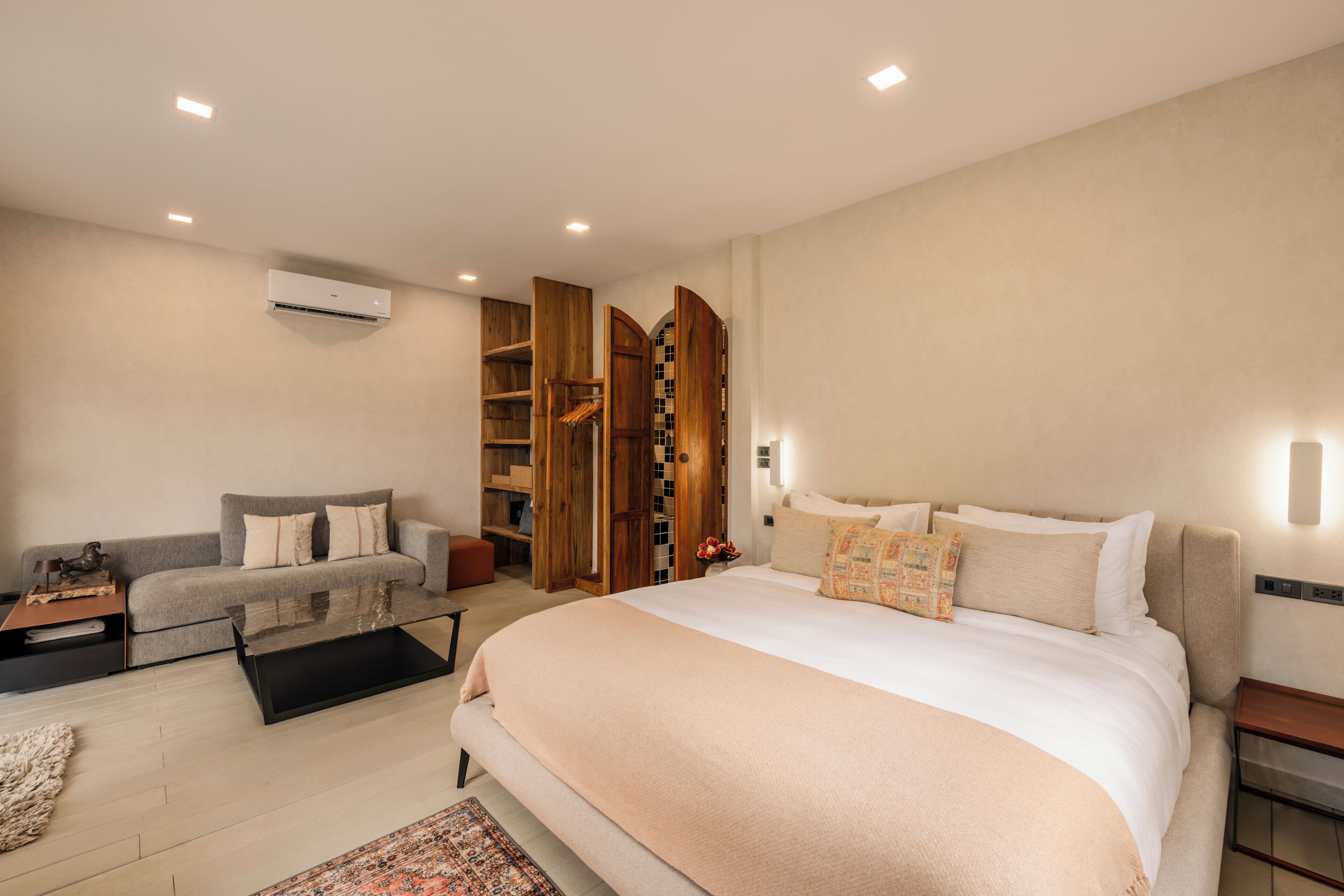 Un dormitorio moderno con una cama grande, un sofá, una mesita de centro y un armario.
