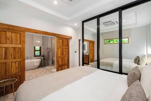 Un dormitorio con una cama grande, un armario de madera y un baño con bañera y retrete.