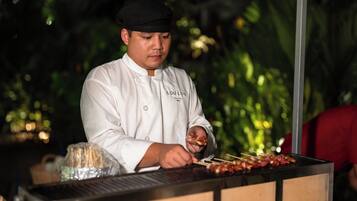 A chef in a white uniform preparing food at a grill station.