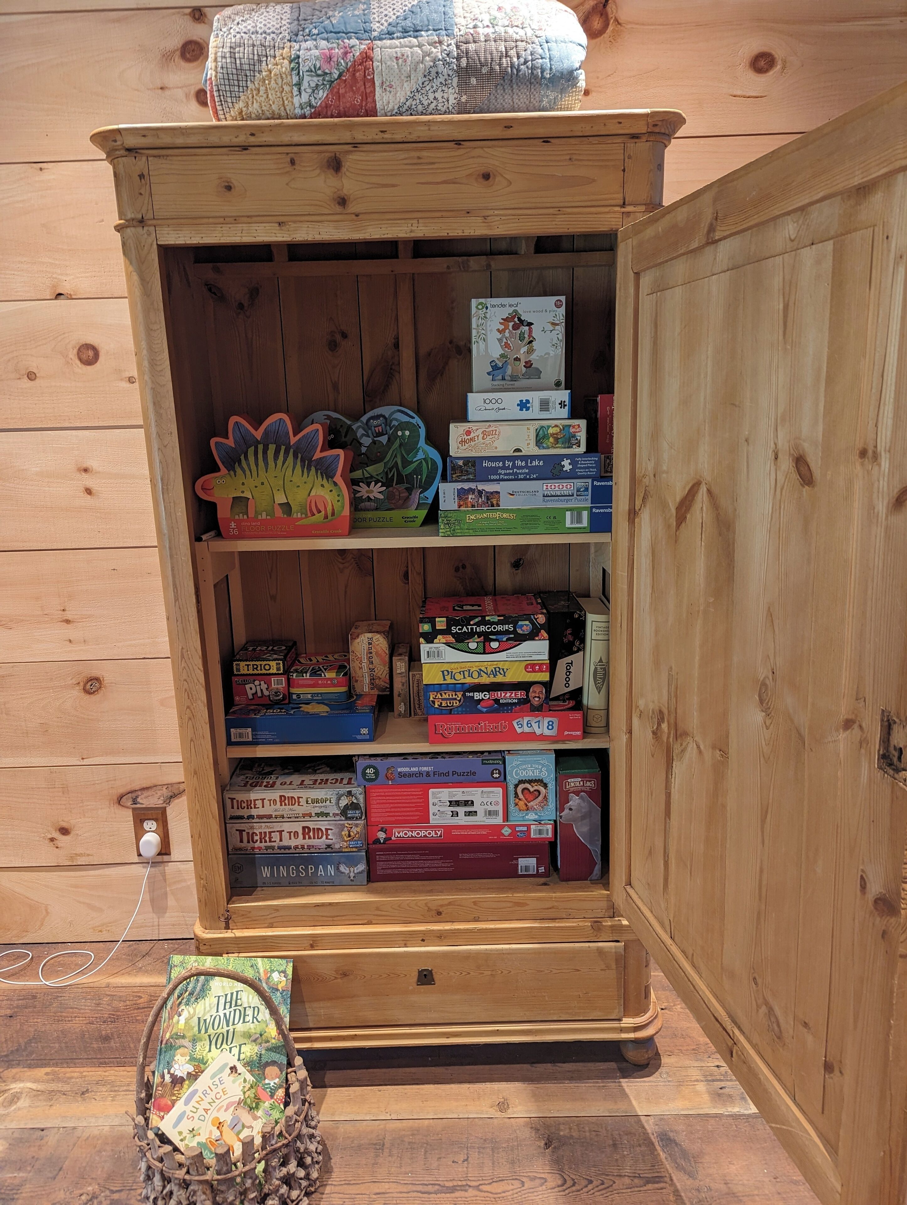 A wooden cabinet with various board games and puzzles.