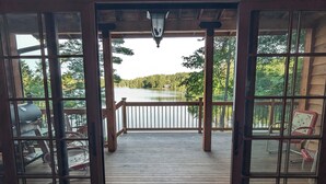 A wooden deck with a pergola, a view of a lake, and outdoor furniture.