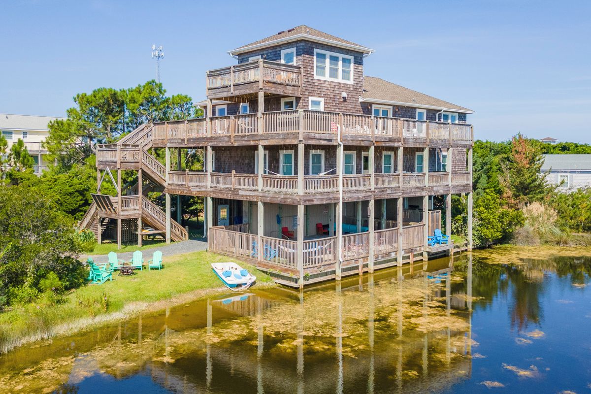 A multi-level waterfront property with a dock and chairs.
