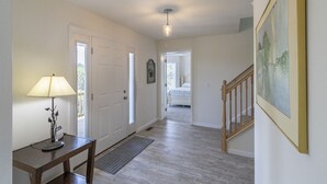 A hallway with a lamp, a door, a staircase, and a painting on the wall.