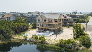 A beachfront house with a pool, deck, and multiple stories.