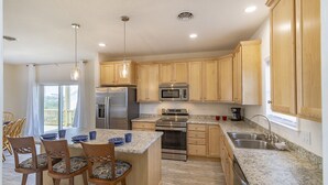 A modern kitchen with wooden cabinets, stainless steel appliances, and a granite countertop.