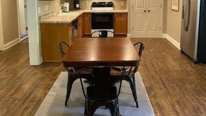 Una cocina moderna con armarios de madera, un refrigerador de acero inoxidable y un comedor con mesa y sillas.