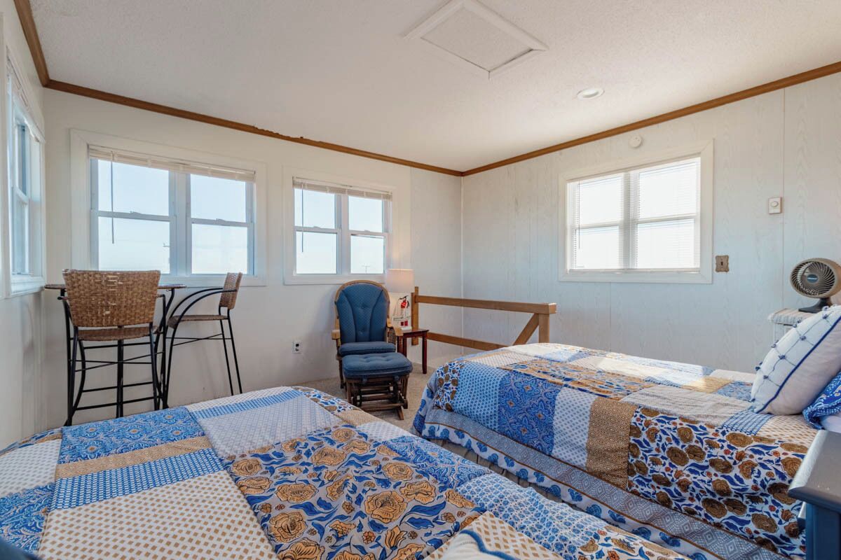 A room with two beds, a chair, a table, and a window.