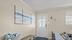 A clean, modern entryway with a bench, a wicker basket, and a couch. - Throw Em Back Inn, Dog Friendly! (Port Aransas)