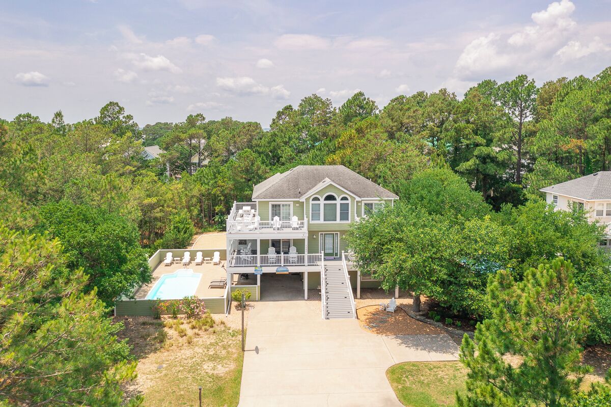 A two-story house with a covered patio and a swimming pool.
