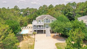 A two-story house with a covered patio and a swimming pool. - Spacious Oceanside Home w/ Pool, Hot Tub, Tiki Bar, & Rec Room (Corolla)
