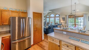 A modern kitchen with stainless steel appliances, wooden cabinets, and a large island. - Spacious Oceanside Home w/ Pool, Hot Tub, Tiki Bar, & Rec Room (Corolla)
