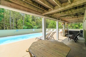 Un espace extérieur abrité comprenant une piscine, des chaises longues et un barbecue.