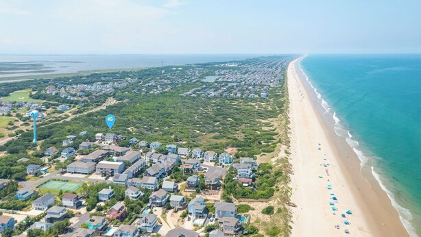 Ein Luftbild einer Küstenwohngegend mit Häusern, einem Strand und blauem Himmel.