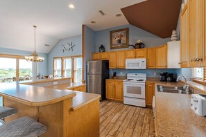 A kitchen with wooden cabinets, a stainless steel refrigerator, a white stove, and a granite countertop.