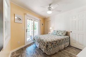 Une chambre à coucher avec un lit, un ventilateur de plafond, une porte et une fenêtre.