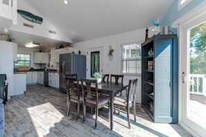 Une cuisine spacieuse avec un coin repas, comprenant un grand îlot central, des appareils modernes et une vue sur l’extérieur.