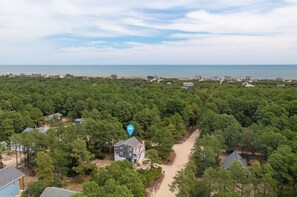 An aerial view of a coastal area with dense forestation and scattered houses. - Pet-Friendly Oceanside Home on the Beautiful 4x4 Beaches (Carova)