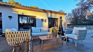 Une terrasse extérieure au design moderne, comprenant un ensemble de canapés, une table agrémentée d’un vase de fleurs et une lanterne décorative.