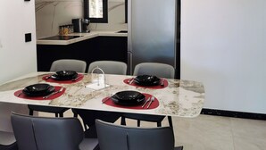 Un espace repas moderne avec une table en marbre, des chaises noires et un luminaire contemporain.