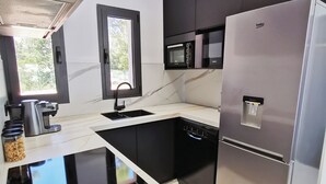 Une cuisine moderne équipée d’un réfrigérateur en acier inoxydable, d’un four à micro-ondes encastré, d’une machine à café et d’un lave-vaisselle.