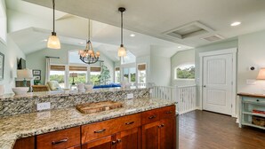 A spacious kitchen with granite countertops, wooden cabinets, and pendant lighting.