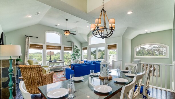 A spacious dining area with a large table set for six, surrounded by white chairs.