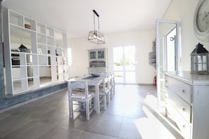 A spacious kitchen with a dining area, white cabinetry, and a large window allowing natural light.