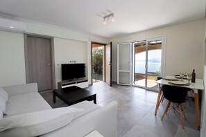 Una sala moderna con sofá, televisión y comedor con vistas.