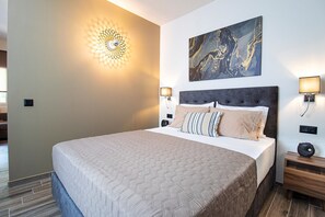 Un lit bien fait, recouvert d’une couvre-lit à motifs, un luminaire fixé au mur, une œuvre d’art en marbre et une table de chevet avec une lampe.