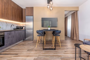 Une cuisine moderne avec des meubles de couleur sombre, un four encastré et un réfrigérateur en acier inoxydable.