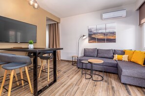 Un salon moderne avec un téléviseur à écran plat, un canapé, une petite table et un coin bar.