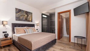 Une chambre moderne avec un grand lit, des lampes de chevet, une télévision et un plancher en bois.