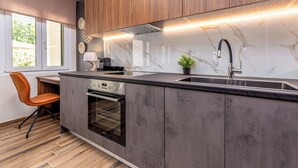 Une cuisine moderne dotée d’un four encastré, d’un évier et d’une fenêtre donnant sur un espace verdoyant.