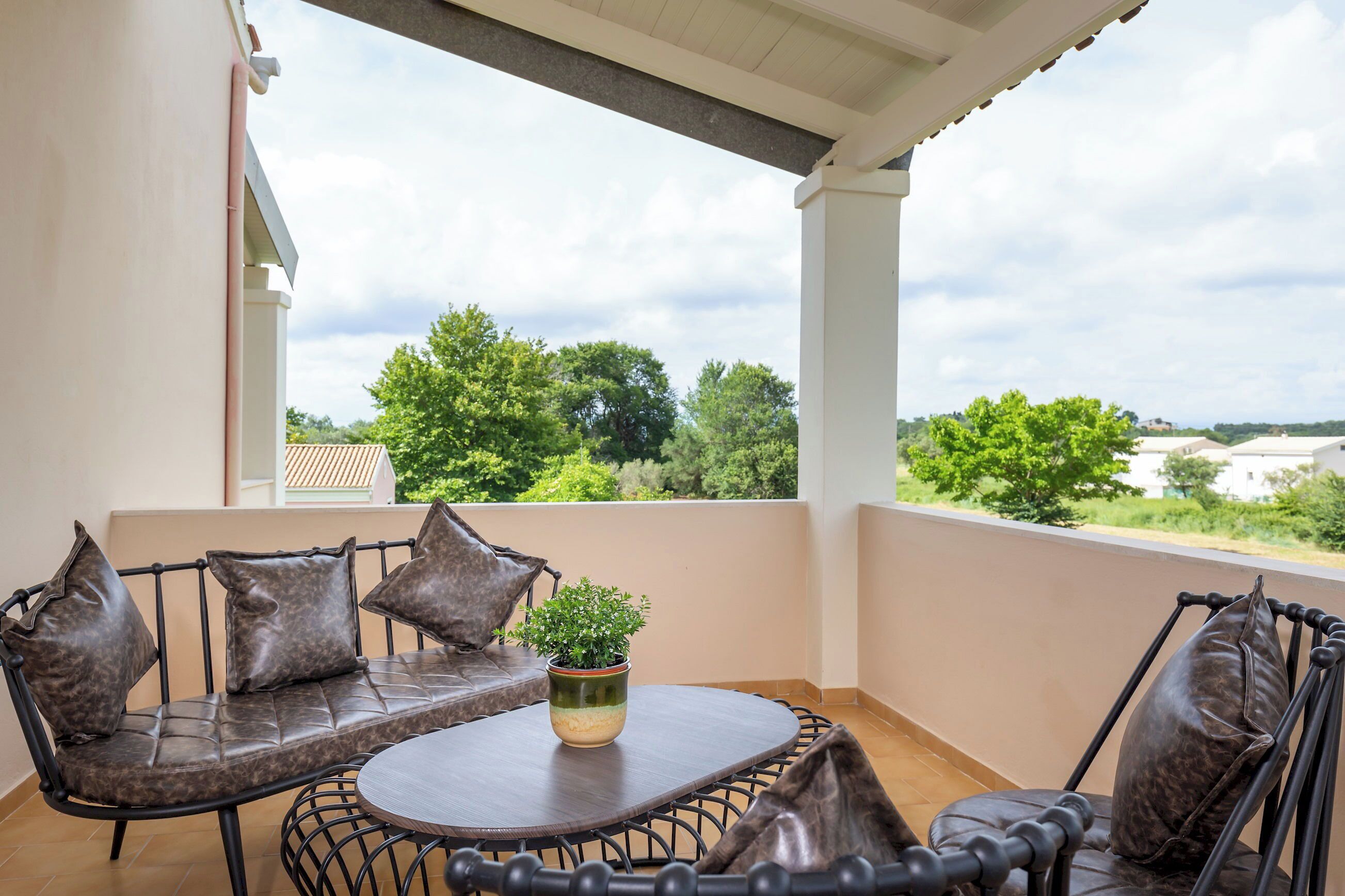 Un balcón con una mesa redonda, dos sillas y una planta en maceta.