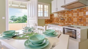 Une cuisine avec une table à manger pour quatre personnes, un four encastré et une vue par la fenêtre.
