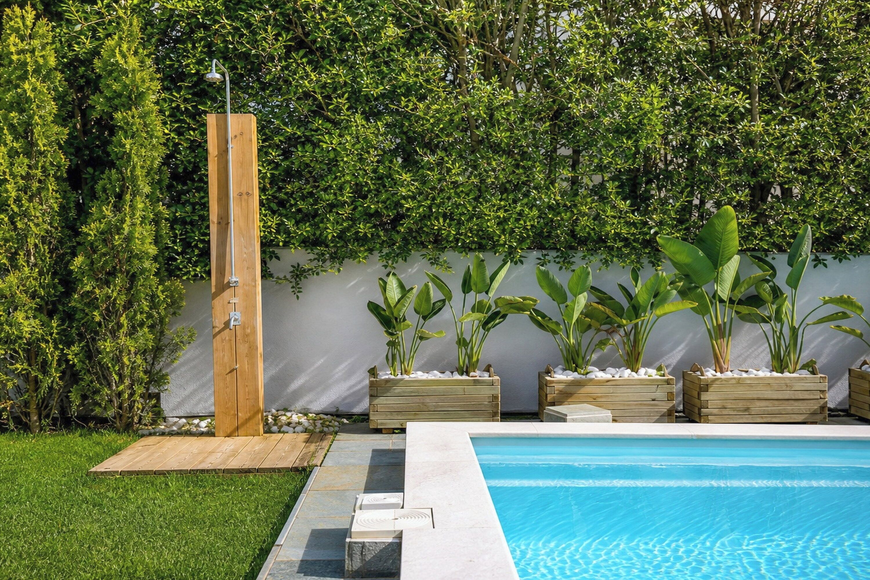 A swimming pool with a wooden deck, a wooden shower enclosure, and potted plants.