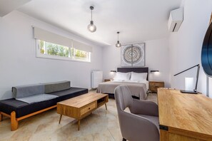Ein modernes Schlafzimmer mit Bett, Nachttischen, einer Sitzecke, einem Schreibtisch und einem Stuhl.