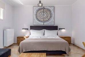 A modern bedroom with a large bed, bedside tables, a wooden nightstand, a wall-mounted light fixture, and a ceiling light.