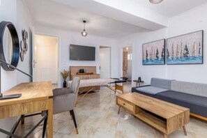 Een moderne woonkamer met een houten bureau, een bank, een televisie en kunst aan de muur.