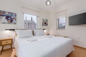 Een slaapkamer met een groot bed, twee nachtkastjes, een flatscreen televisie en abstracte kunst aan de wanden.