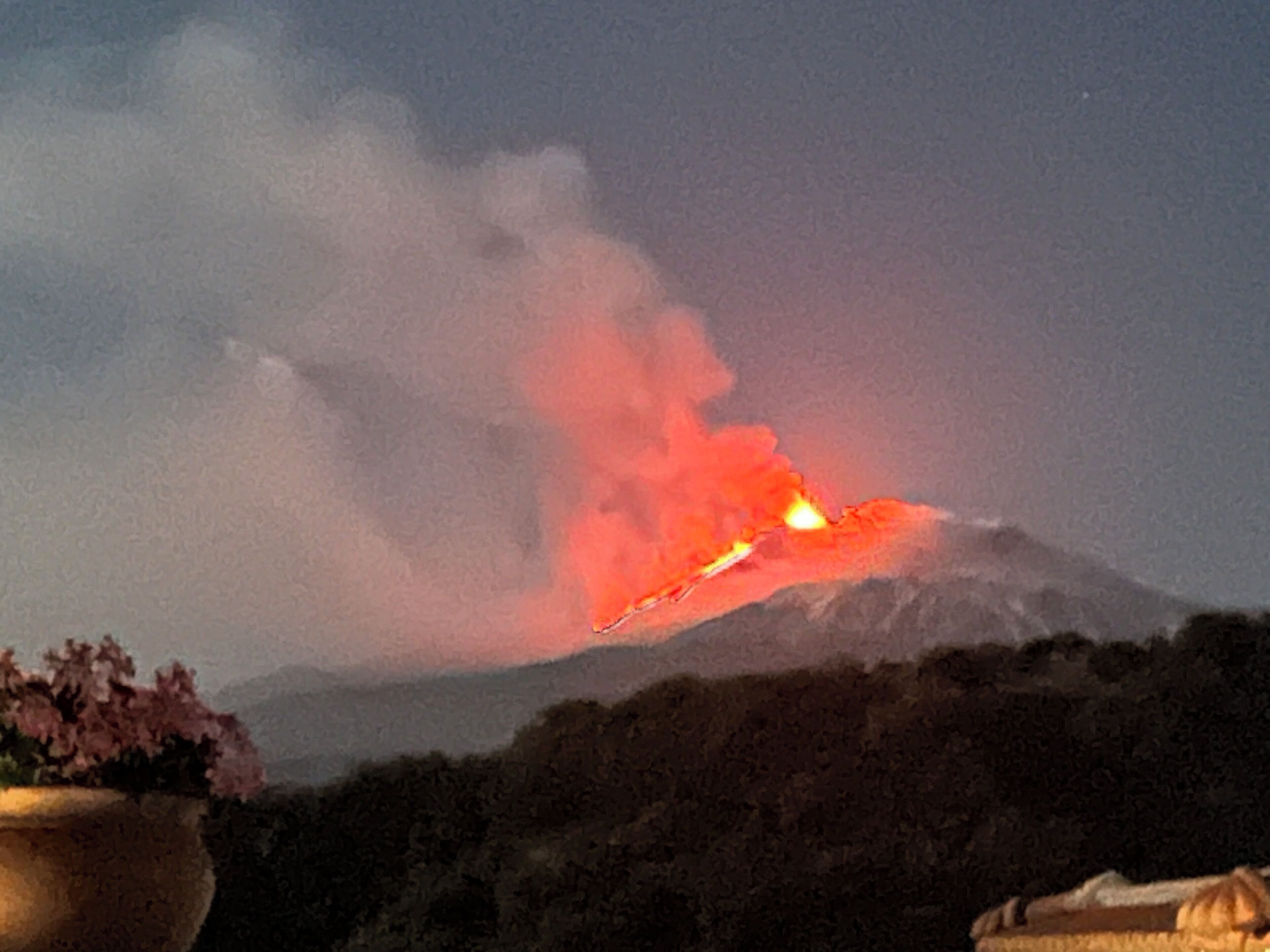 Un volcán con un flujo de lava activo y humo.