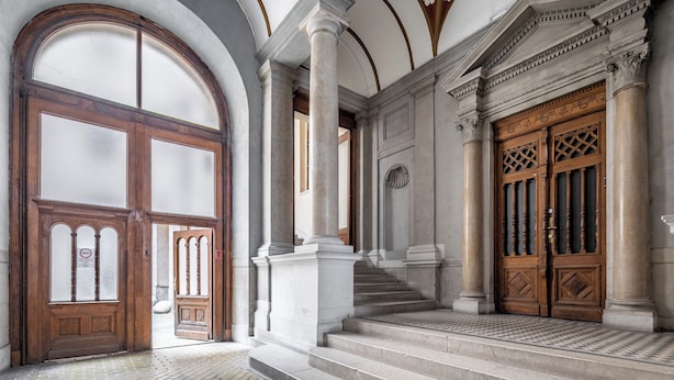 A grand entrance with large wooden doors, a marble staircase, and classical architectural elements. - Budapest Marvelous Apartment (Budapest)