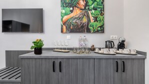 A modern kitchen with grey cabinetry, a flat-screen TV mounted above the counter, and a painting of a woman on the wall. - Budapest Marvelous Apartment (Budapest)