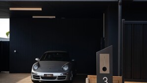 A silver Porsche parked in a dark garage with a wooden number 3 sign. - Chalet Noir- sleek design with heated plunge pool, close to town (Daylesford)
