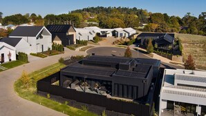 A modern residential area with multiple houses featuring solar panels, a central driveway, and a landscaped garden. - Chalet Noir- sleek design with heated plunge pool, close to town (Daylesford)
