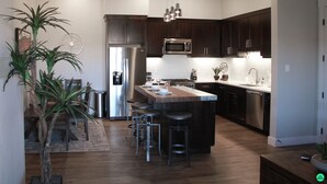 Una cocina moderna con armarios de madera oscura, electrodomésticos de acero inoxidable y una isla central con taburetes.